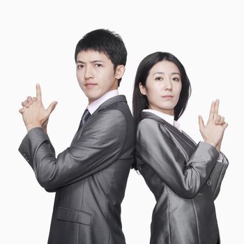Businessman and businesswoman standing back to back and showing hand guns