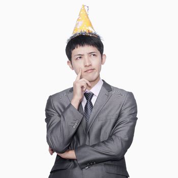 Businessman thinking, wearing party hat