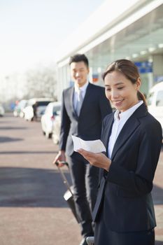 Traveler looking at ticket at airport arrivals area