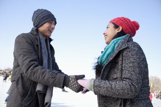 Young couple holding hands at ice rink