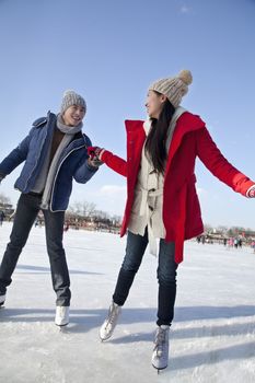 Young couple skating at ice rink