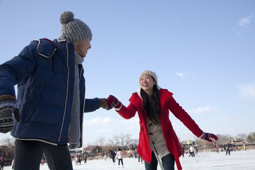 Young couple skating at ice rink