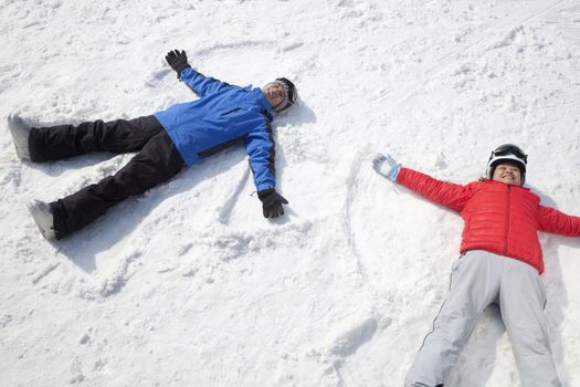 Couple Lying On Snow Making Snow Angel