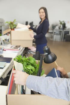 Two young business people carrying boxes with office items