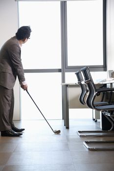 Businessman playing golf in his office