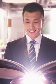 Young smiling businessman reading a book