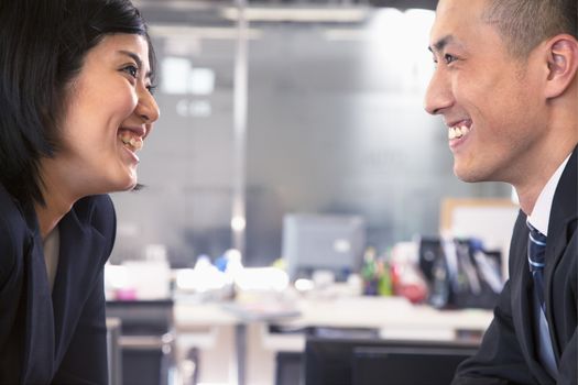 Two business people smiling and laughing face to face