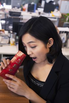 Young businesswomen looking into traditional red envelopment, Chinese New Year