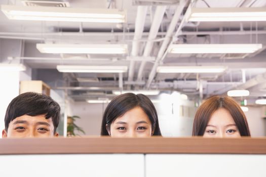 Office workers peeking over divider in office