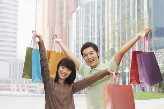 Portrait of young couple posing with shopping bags in hands, Beijing, China 