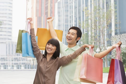 Portrait of young couple posing with shopping bags in hands, Beijing, China 