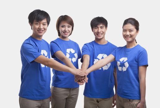 Four young people in recycling t-shirts with hands together, studio shot