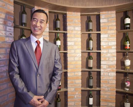 Smiling Businessman Standing by Wine Bottles