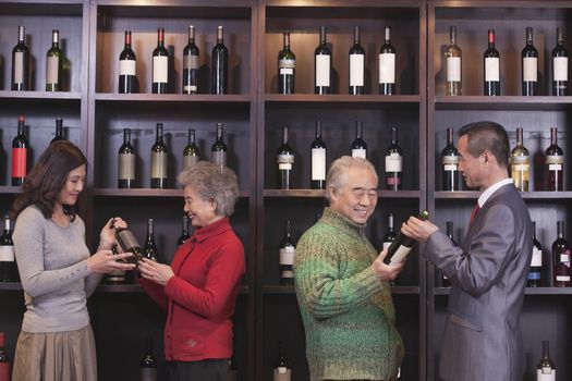 Four People Examining Wine Bottles at a Wine Store