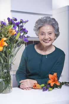 Senior Woman Beside Bouquet of Flowers in the Kitchen, Portrait