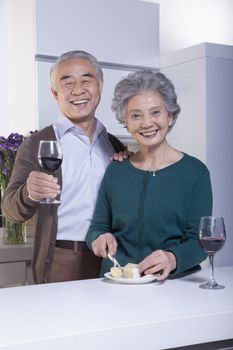 Senior Couple in Kitchen Drinking Wine and Cheese