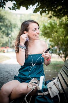 beautiful woman listening to music with phone player in the city