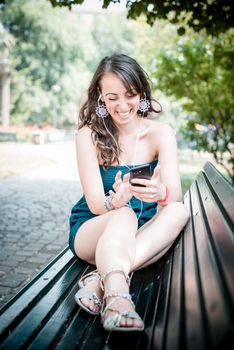 beautiful woman listening to music with phone player in the city