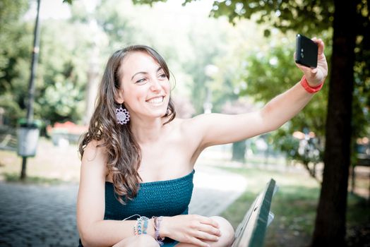 beautiful woman taking self-portrait with smart-phone in the city