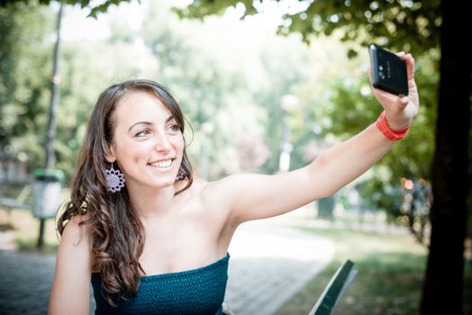 beautiful woman taking self-portrait with smart-phone in the city