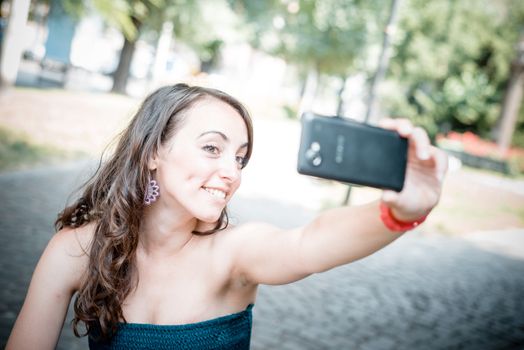 beautiful woman taking self-portrait with smart-phone in the city