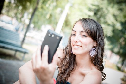 beautiful woman taking self-portrait with smart-phone in the city