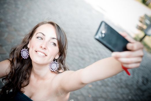 beautiful woman taking self-portrait with smart-phone in the city