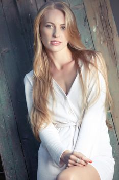 Blond lady in countryside standing against the wooden plate