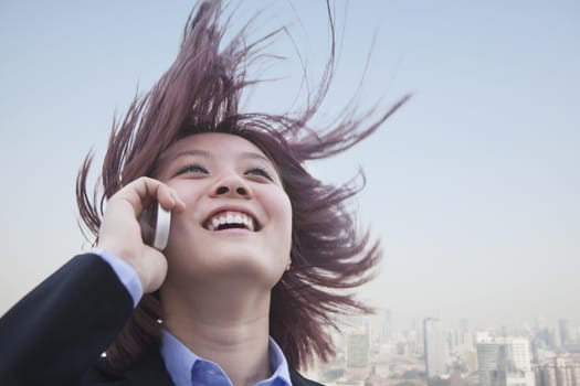 Young businesswoman smiling using her cell phone with hair blowing