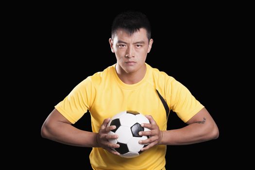 Footballer player holding ball to chest, black background