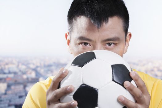 Footballer holding ball against his face