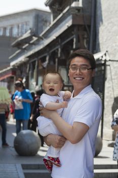 Portrait of father holding his baby son, outdoors Beijing