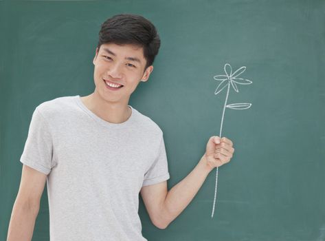 Portrait of young man in front of chalkboard with flower drawing   