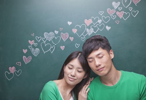 Young couple in front of blackboard with hearts     