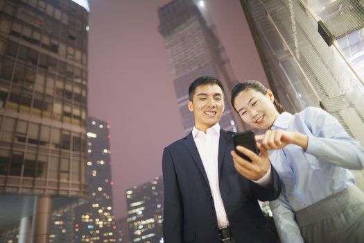 two business people smiling and looking at the phone 