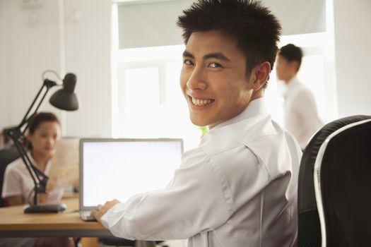 Man working on her laptop and smiling in the office 