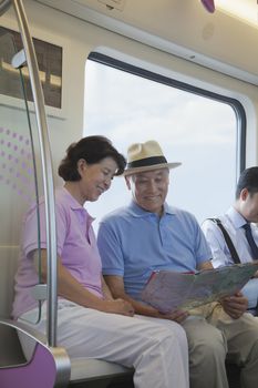 Mature couple sitting in the subway and looking at the map