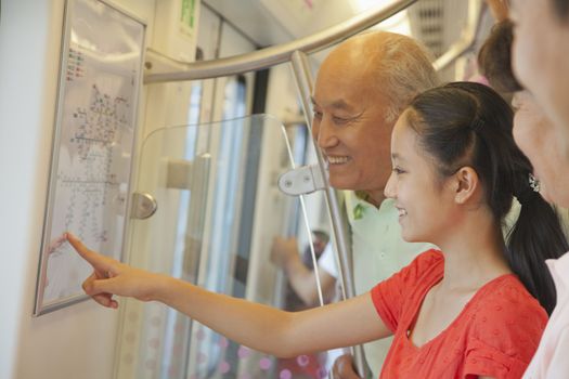 Granddaughter with grandparents standing in the subway and looking at the map