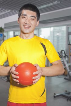 Man holding ball in his hands in the gym 