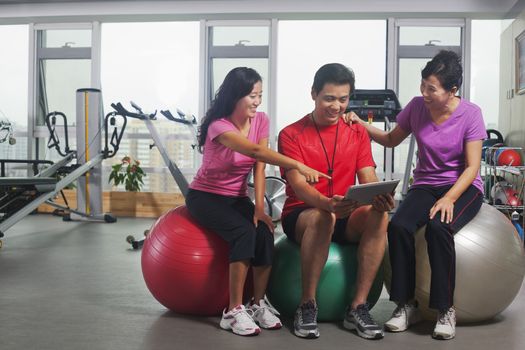 People looking at digital tablet in the gym