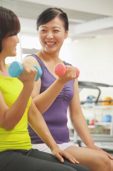 Two mature women lifting weights in the gym 