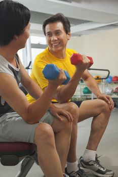 Two mature men lifting weights in the gym 