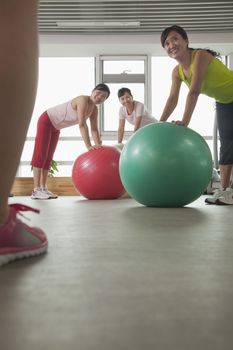 mature women exercising with fitness ball and looking at the trainer