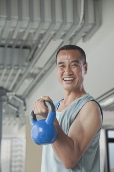 Mature man lifting weights in the gym, portrait 