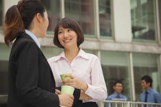 Businesswomen talking and drinking coffee outdoors