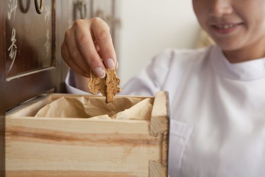 Doctor Taking Herb Used for Traditional Chinese Medicine Out of a Drawer