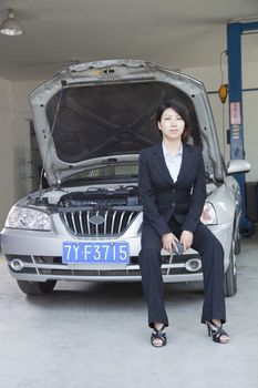 Businesswoman Sitting on Car With Open Hood