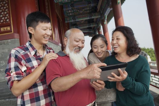 Chinese Family Looking At Digital Tablet In Jing Shan Park