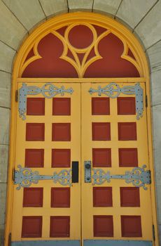 Old red and yellow ornate church door in wooden wall