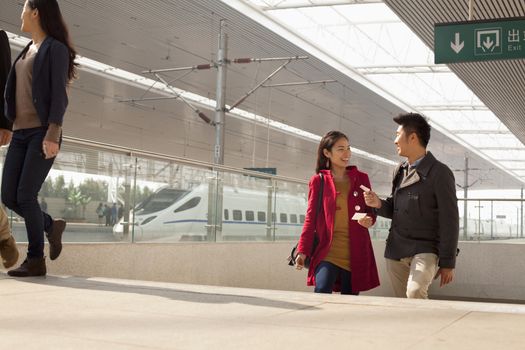 Young woman talking to man on railway platform, China